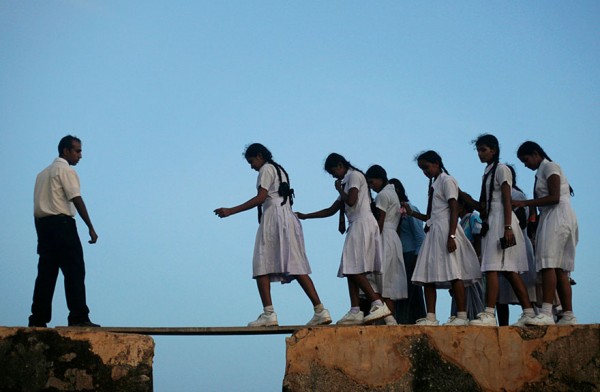 Alumnas cruzando a través de una tabla en la gran fortaleza de Galle del siglo XVI en Sri Lanka