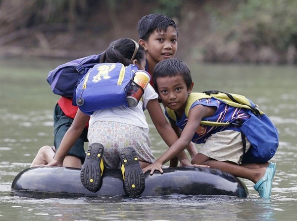 Alumnos de primaria cruzan el rió con la cámara de un neumático inflado, Provincia de Rizal, Filipinas
