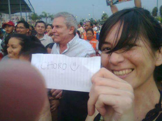 En la imagen aparece una joven que sostiene un pedazo de papel donde está escrito la frase “choro”, mientras detrás de ella se encuentra un grupo de personas celebrando la entrada de Luis Castañeda, candidato a la alcaldía por Solidaridad Nacional.