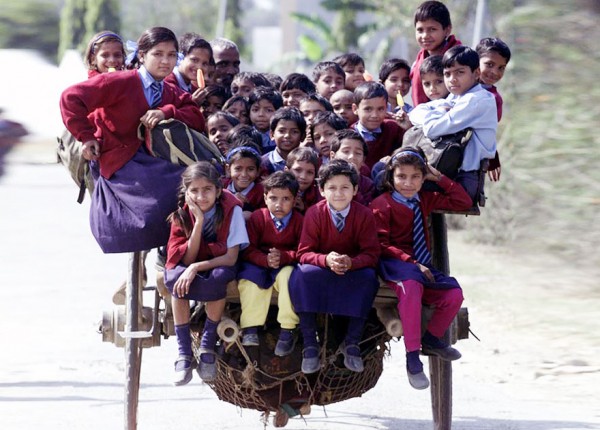 Escolares encima de un carro jalado por un caballo en Delhi, India